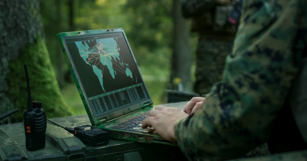 Sotilas katsoo tietokoneelta maailmankarttaa metsässä