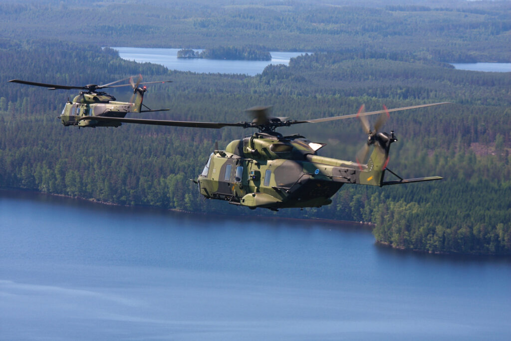 Kaksi NH90 sotilashelikopteria lentää järven yllä kuvattuna ilmasta
